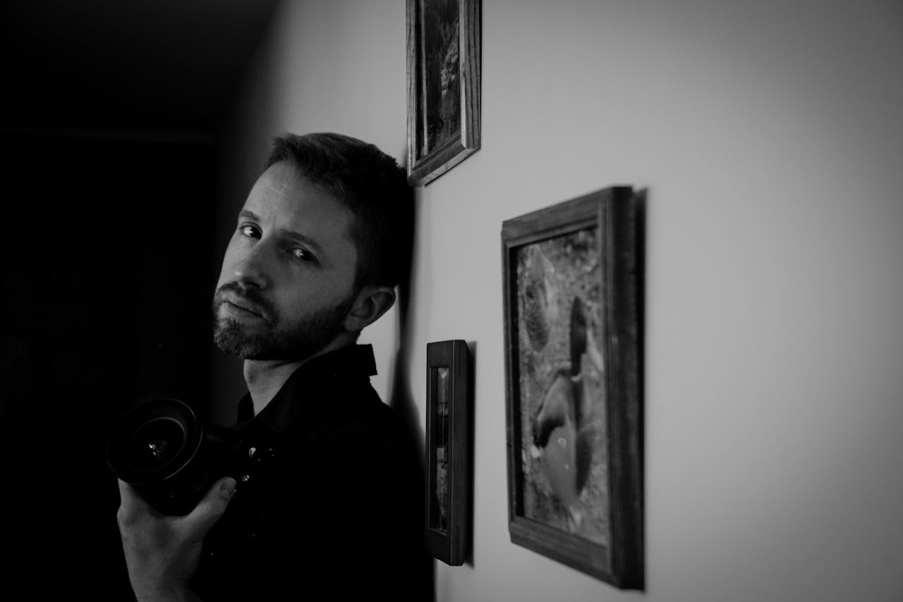 services-03 A contemplative male photographer holding a camera in a black and white composition.