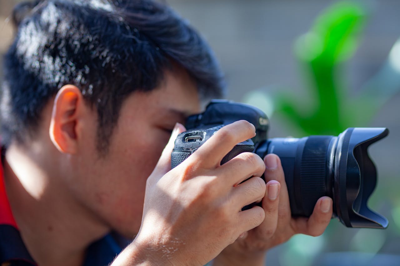 our-journey-01 An adult male photographer takes a picture with his DSLR camera outdoors on a sunny day.